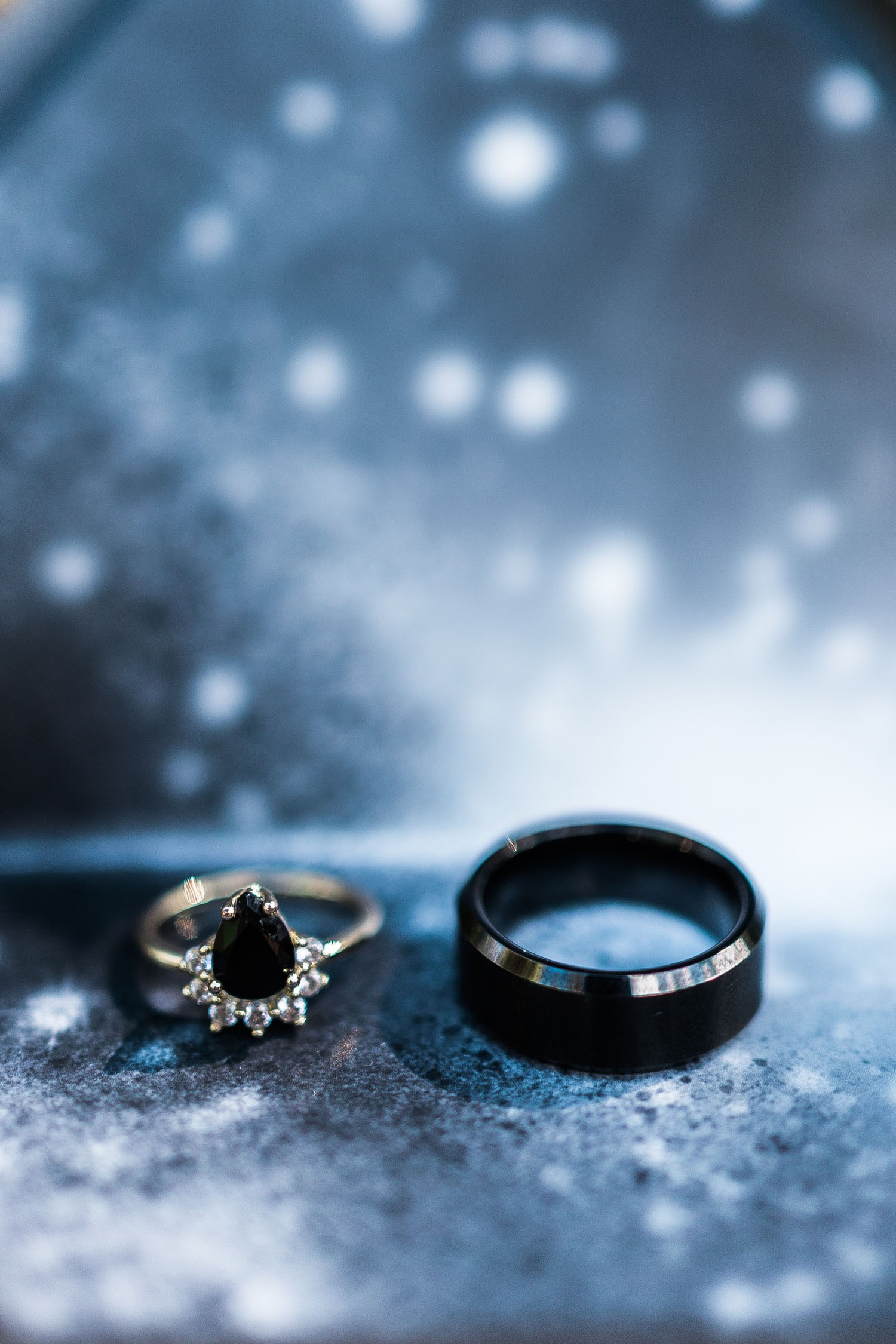 mens black wedding bands sitting on a glittering blue backdrop